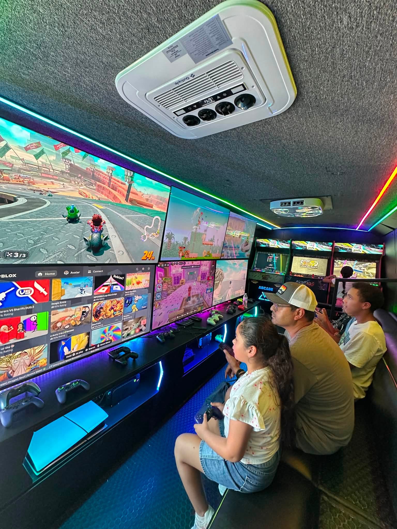 A family playing together at the console stations inside the RGV Games on Wheelz mobile gaming bus